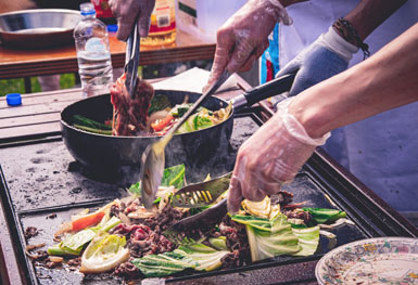 manos asando carne y verduras