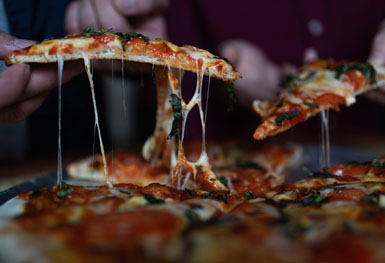 manos sacando porción de una pizza